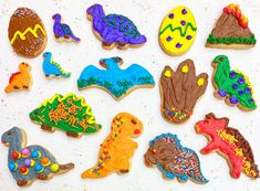 decorated cookies in the shape of dinosaurs on a white surface with sprinkles