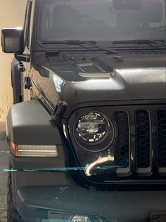 the front end of a black jeep parked in a parking lot