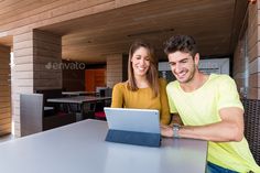 a man and woman sitting at a table with a laptop computer