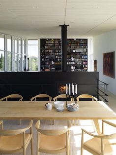 a dining room table with chairs and bookshelves in front of an open fire place