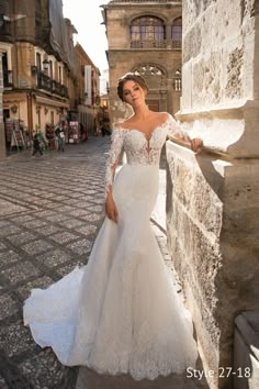 a woman in a wedding dress leaning against a stone wall