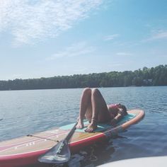 a woman laying on top of a surfboard in the water