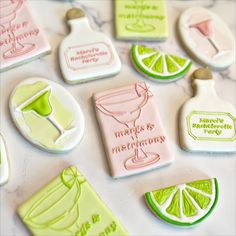 decorated cookies are arranged on a table with lemons, lime and cocktail bottles in the background