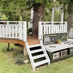 an outdoor kitchen built into the side of a wooden deck with stairs leading up to it