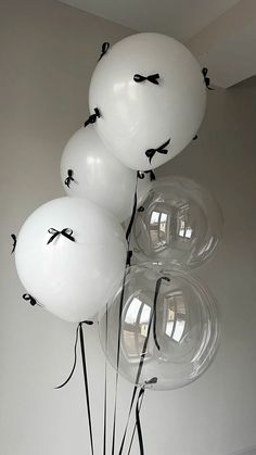 white balloons with black bows tied to them are in a vase on the floor next to a wall