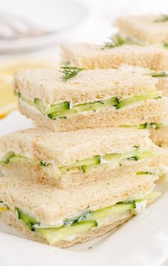 four sandwiches stacked on top of each other with cucumber and dill in the middle