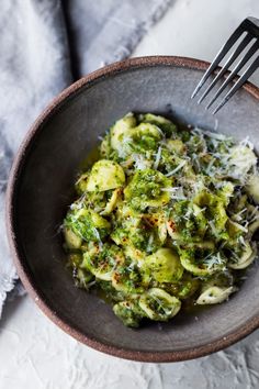 a bowl filled with broccoli and cheese on top of a white table cloth