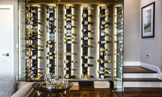 a wine rack in the corner of a living room with stairs leading up to it