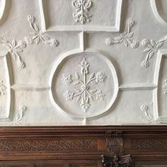 an ornately decorated ceiling in a room with wood paneling and white paint on the walls