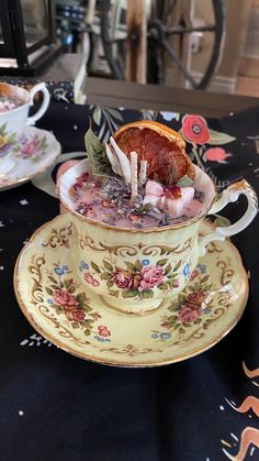 a tea cup with an orange slice in it on top of a table next to other cups and saucers