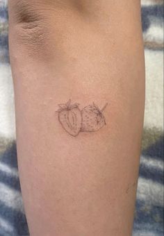 a tattoo on the leg of a woman with two strawberries and an apple in it