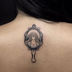 a woman's back with a mirror tattoo on it