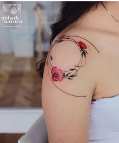 a woman's shoulder with flowers on it and a circular tattoo design in the middle