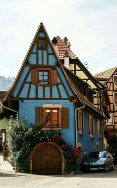 a car parked in front of a blue house with brown shutters and wooden windows