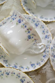 a table topped with lots of white and blue plates covered in gold trimmings