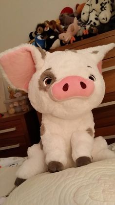 a stuffed pig sitting on top of a bed