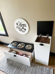 a dog house with two bowls on the floor and a sign above it that says welcome to our dogs