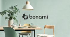 a dining table with two chairs and a plant on top of it, in front of the wall that says bonami