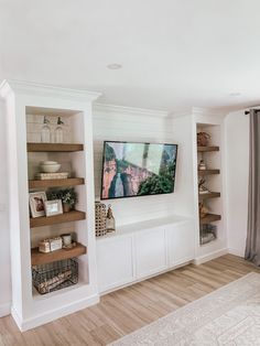 a living room filled with furniture and a flat screen tv on top of a wooden shelf