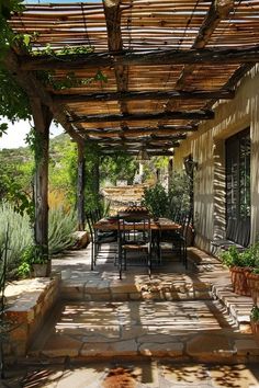 an outdoor dining area with tables and chairs under a pergolated roof, surrounded by greenery