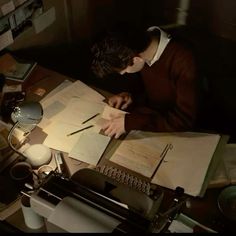 a man sitting at a desk writing on an old fashioned typewriter in the dark