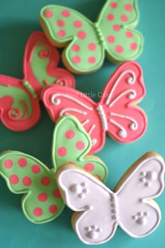 decorated cookies in the shape of butterflies on a blue tablecloth with pink and green polka dots