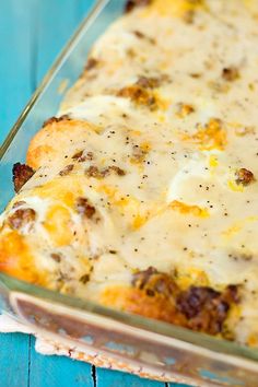 a casserole dish with cheese and meat in it sitting on a blue table