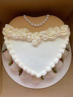 a heart shaped cake with white frosting and strawberries on the bottom is in a box