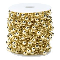 a spool of gold colored beads on a white background