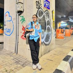 a young man standing next to a wall covered in graffitti and writing on it