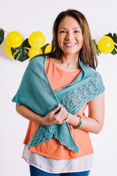 a woman is smiling while holding a shawl in front of balloons and lemons