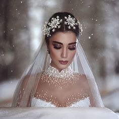 a woman wearing a wedding dress and veil with snow falling on her face in the background