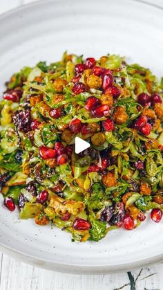 a white plate topped with broccoli and pomegranate