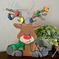 a wooden reindeer sitting on top of a table next to a potted green plant