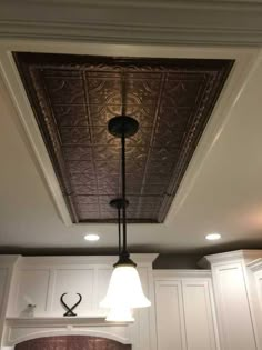 a kitchen with white cabinets and an overhead light fixture in the center of the room