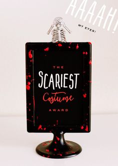 the scariest costume award is displayed on a black stand with red splatters