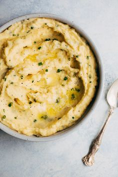 a bowl filled with mashed potatoes on top of a blue tablecloth next to a spoon