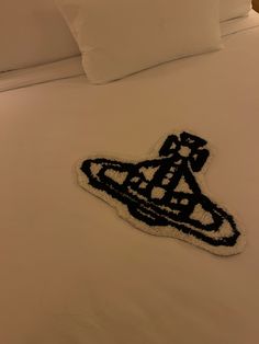 a close up of a bed with white sheets and black decorations on the headboard