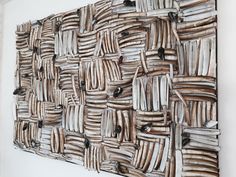 a large piece of art made out of wood sticks and plywood strips on a white wall