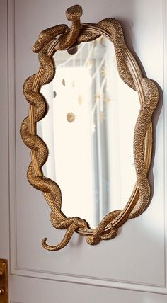 a mirror hanging on the side of a wall next to a door with an intricate design