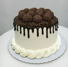 a cake with white frosting and chocolate drizzles on it's top