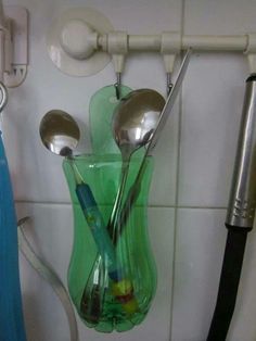 spoons and utensils are hanging on the wall next to a toothbrush holder