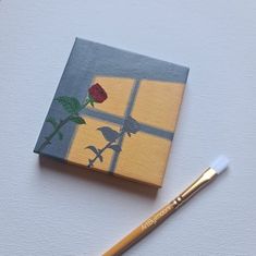 a painting with a rose on it next to a brush