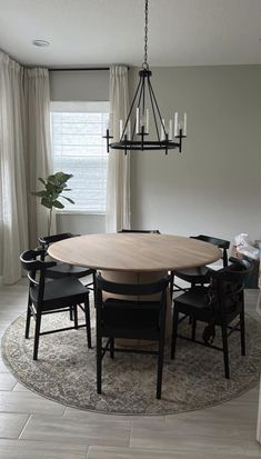 a dining room table and chairs with a rug on the floor in front of it