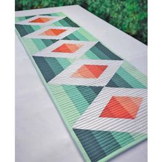 a quilted table runner with an orange, green and white design on it's edge