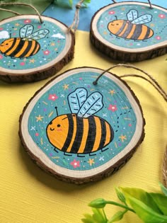 three wooden slices with bees on them sitting on a yellow table cloth next to plants