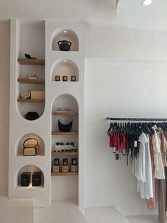 a white closet with shelves, shoes and purses hanging on the wall next to it