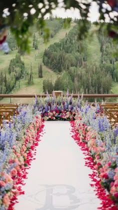 an outdoor ceremony setup with flowers on the aisle