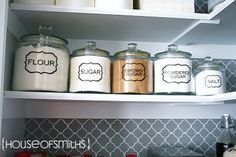 the pantry shelves have jars with labels on them