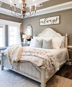 a white bed sitting under a chandelier in a bedroom